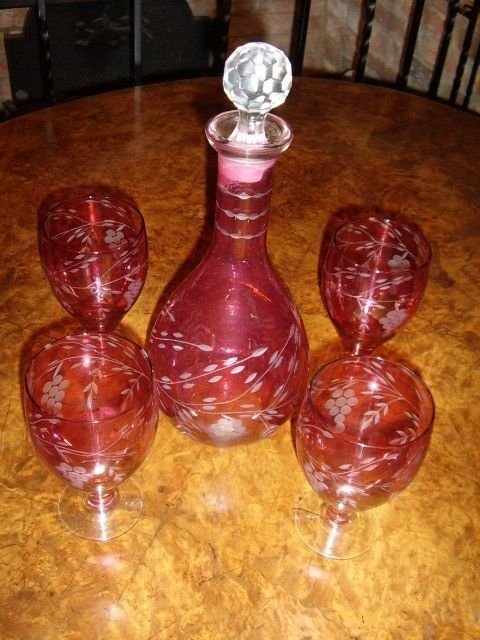 cranberry glass decanter set with four glasses having etched design